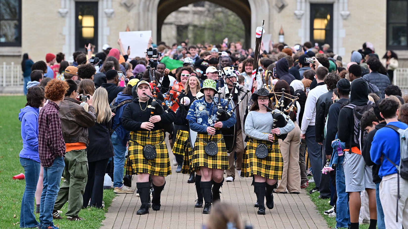 Students in plaid kilts lead a bagpipe parade through cheering crowds during the I.S. Monday celebration at The College of Wooster.